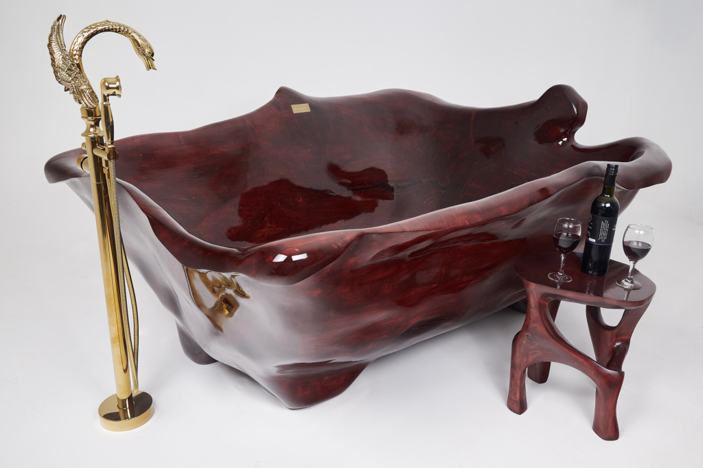 A luxurious, intricately carved red solid wood bathtub, paired with a side table and a gold swan-shaped faucet.