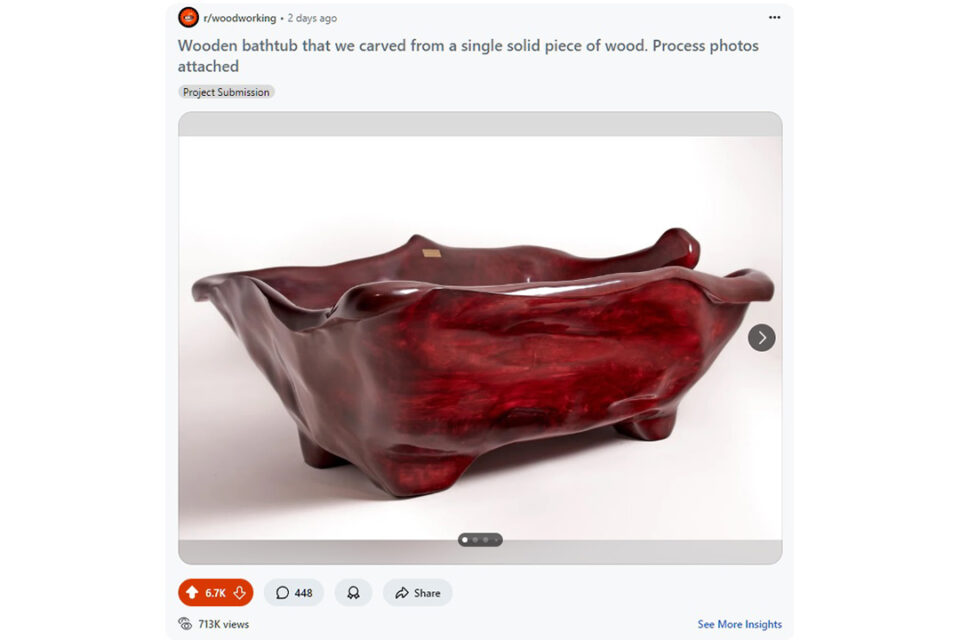 Viral Reddit post of aglossy, deep red wooden bathtub with organic, wavy edges and sculpted legs, carved from a single piece of wood, is displayed against a plain background.