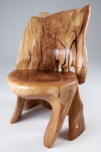 Sculptural chair with a forked, split backrest and flowing curved seat, pale wood marked with dramatic dark streaking.