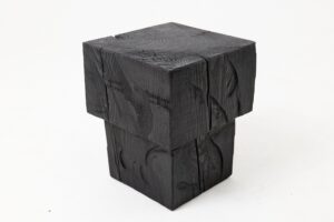 Boxy, tower-like ebonized wood stool with a stepped profile and hand-tooled marks across its charred surface.